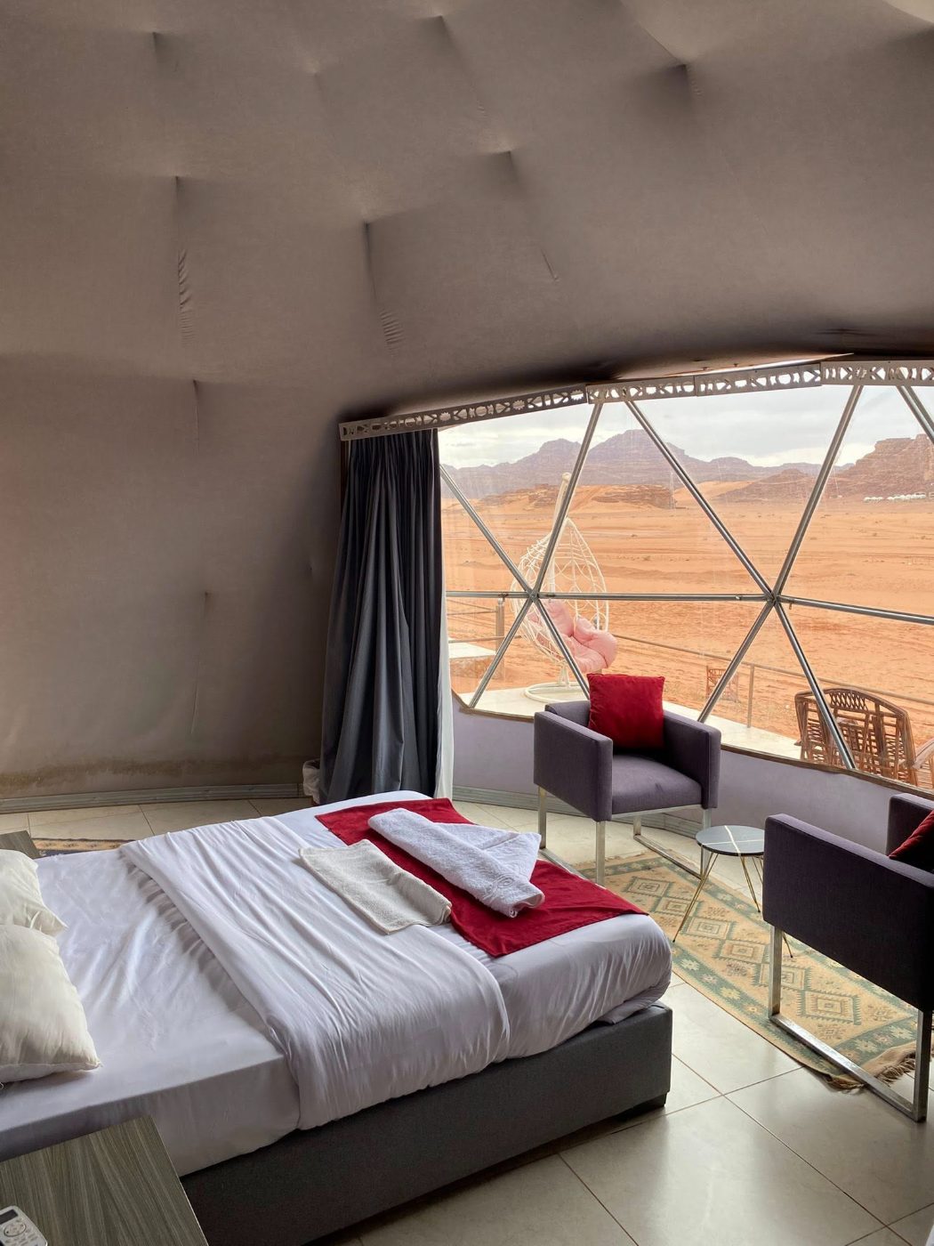A camp bedroom with a window onto the desert